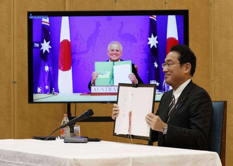 Japan's Prime Minister Fumio Kishida, right, and Australia's Prime Minister Scott Morrison, seen on screen, show off signed documents during a virtual summit to sign the Reciprocal Access Agreement, at Kishida's official residence in Tokyo, Japan Thursday, Jan. 6, 2022.  The leaders of Japan and Australia signed a “landmark” defense agreement Thursday that allows closer cooperation between their militaries and stands as a rebuke to China's growing assertiveness in the Indo-Pacific region. (Issei Kato/Pool Photo via AP)