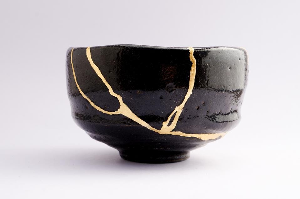 Antique broken Japanese raku black bowl repaired with gold kintsugi technique Antique broken Japanese raku black bowl repaired with gold kintsugi technique