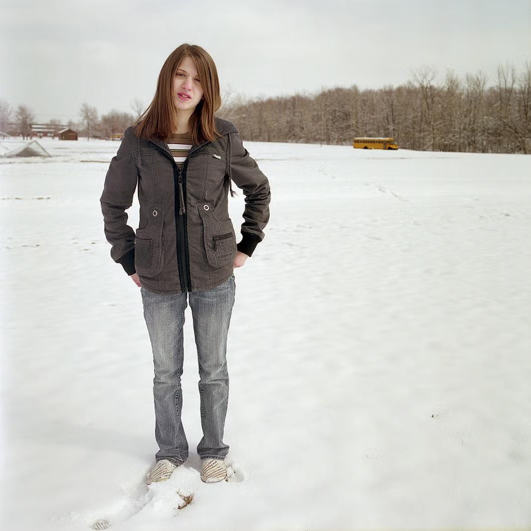 woman with shoulder length hair and a jacket and jeans and sneakers stands in field covered in snow woman with shoulder length hair and a jacket and jeans and sneakers stands in field covered in snow