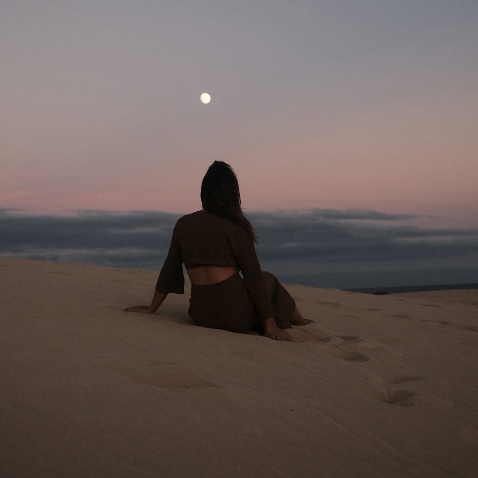a woman sitting on top of a sandy beach a woman sitting on top of a sandy beach