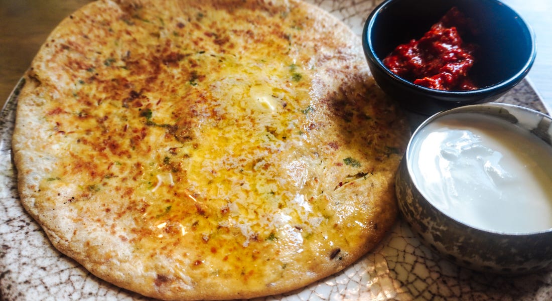 A plate of food with buttery bread, yoghurt, and pickle