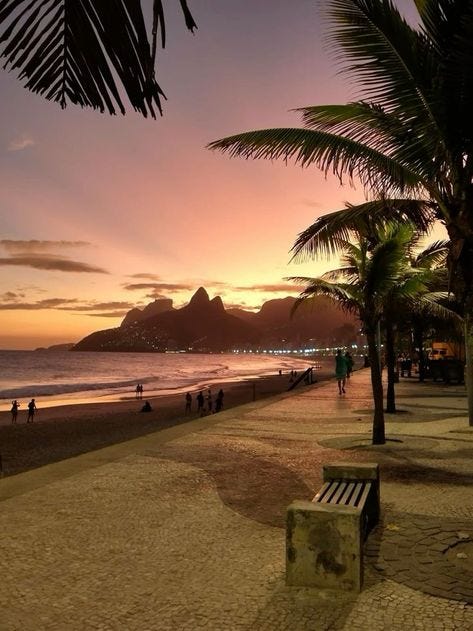 This may contain: people are walking on the beach as the sun goes down and it's setting