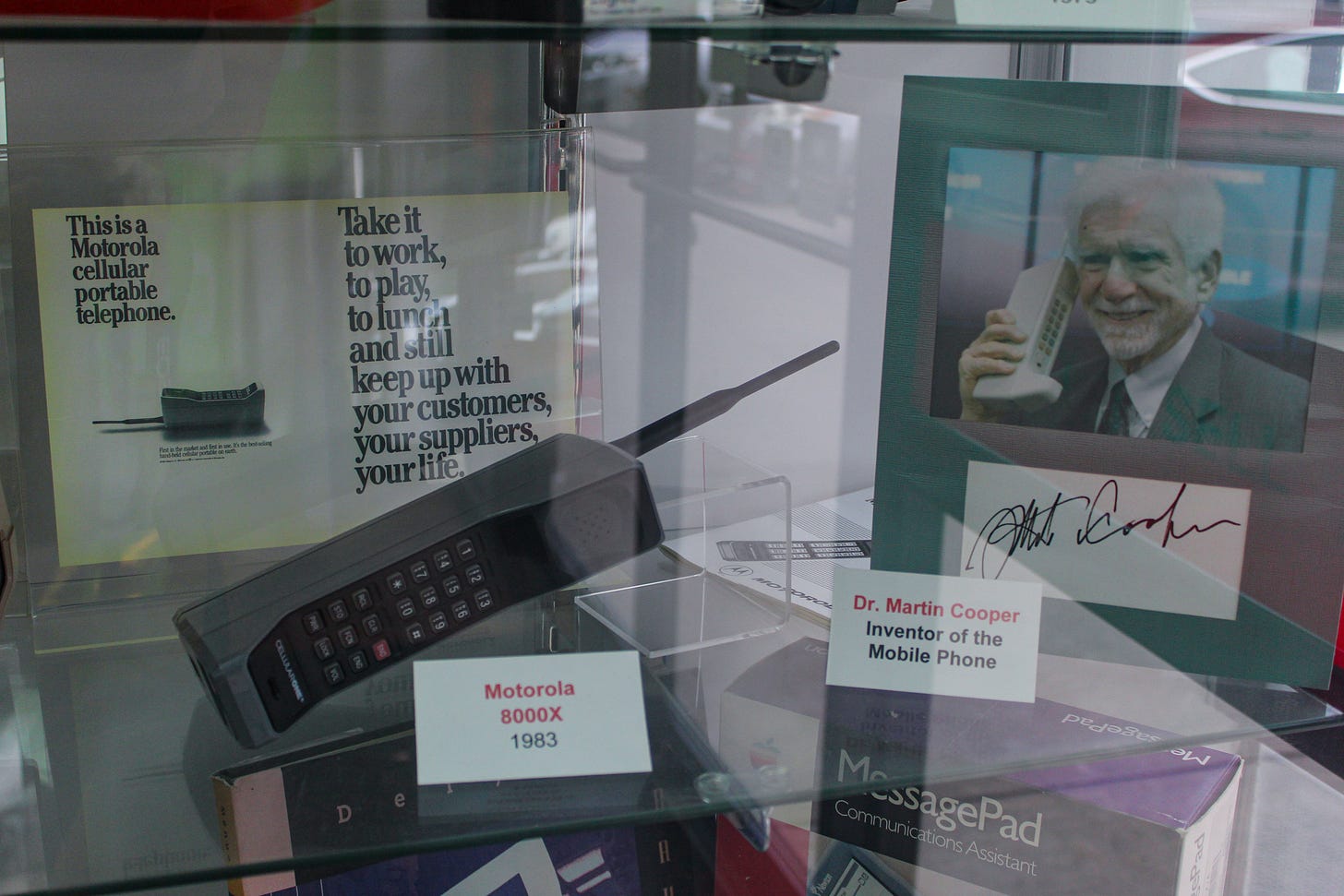 A Motorola 8000X phone and an autographed photo of Martin Cooper in a glass display case