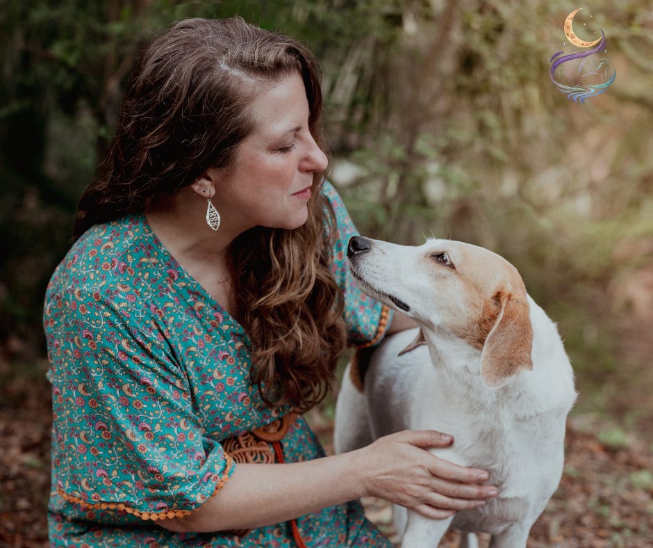 A woman in a blue dress kneels outdoors, hand resting on the chest of a fawn and white hound. Both are looking directly at each other, with oaks and palmettos in the background. A woman in a blue dress kneels outdoors, hand resting on the chest of a fawn and white hound. Both are looking directly at each other, with oaks and palmettos in the background.