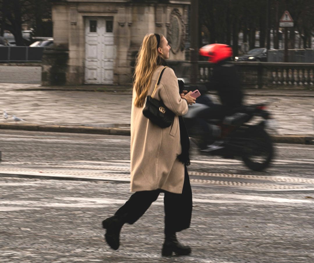 a woman walking down a street next to a clock tower