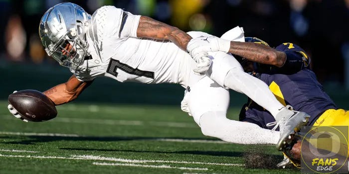 Oregon Ducks wide receiver being tackled by a Michigan defender during a 2024 Big Ten game. The receiver will reportedly miss the 2025 season with an injury.