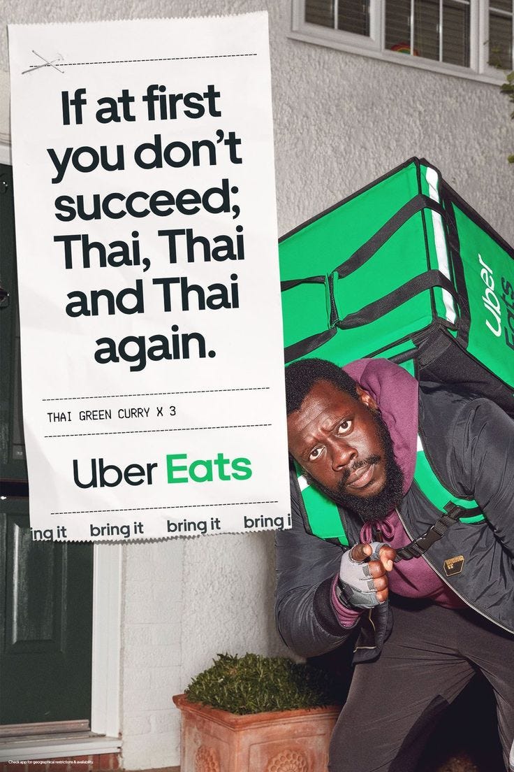 This may contain: a man holding a large green box in front of a sign