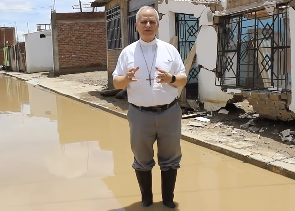 Then-Bishop Robert Prevost, now Pope Leo XIV, stands in floodwaters in the Chiclayo Diocese in the aftermath of heavy rains in northwestern Peru in March 2023, in this screenshot from a video by Caritas Chiclayo (NCR screengrab/Caritas Chiclayo)