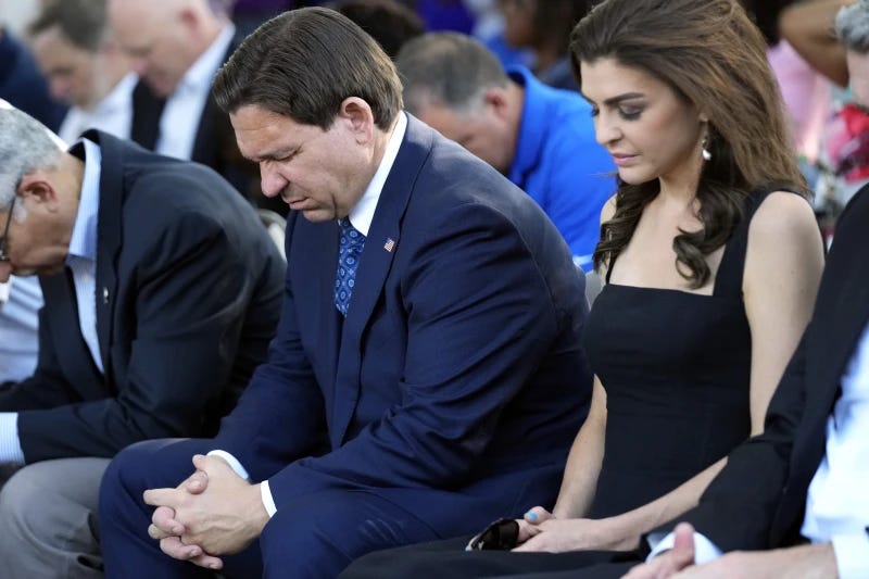 Florida Gov. Ron DeSantis, center and his wife Casey, right, bow their heads during a prayer at a vigil for the victims of Saturday’s mass shooting Sunday, Aug. 27, 2023, in Jacksonville, Fla. (AP Photo/John Raoux)