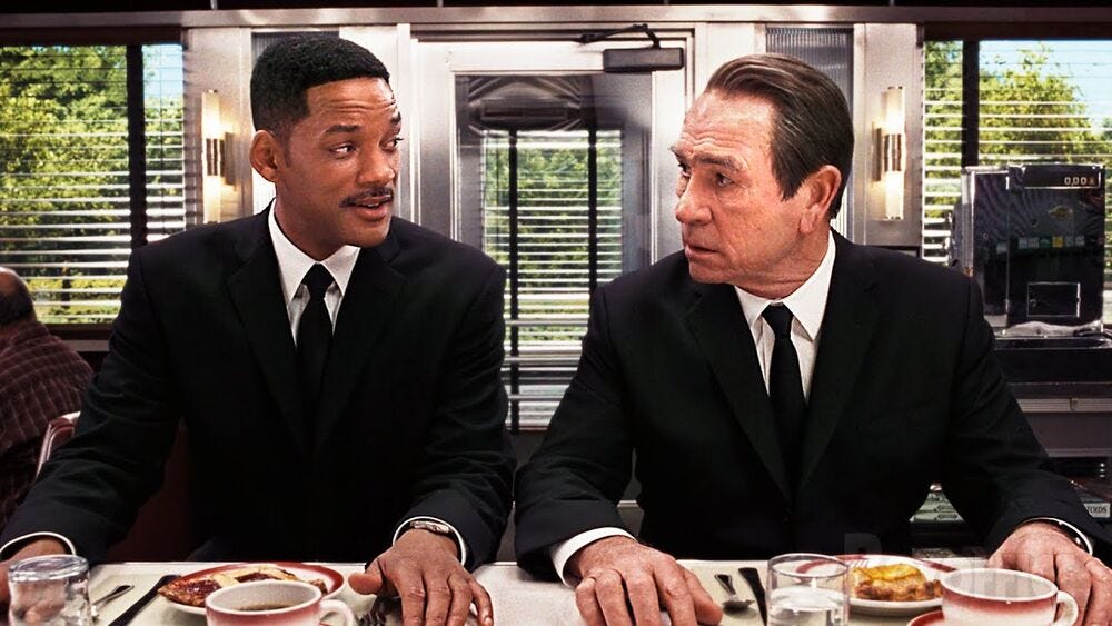 a diner scene from men in black featuring the two main characters enjoying pie in a diner