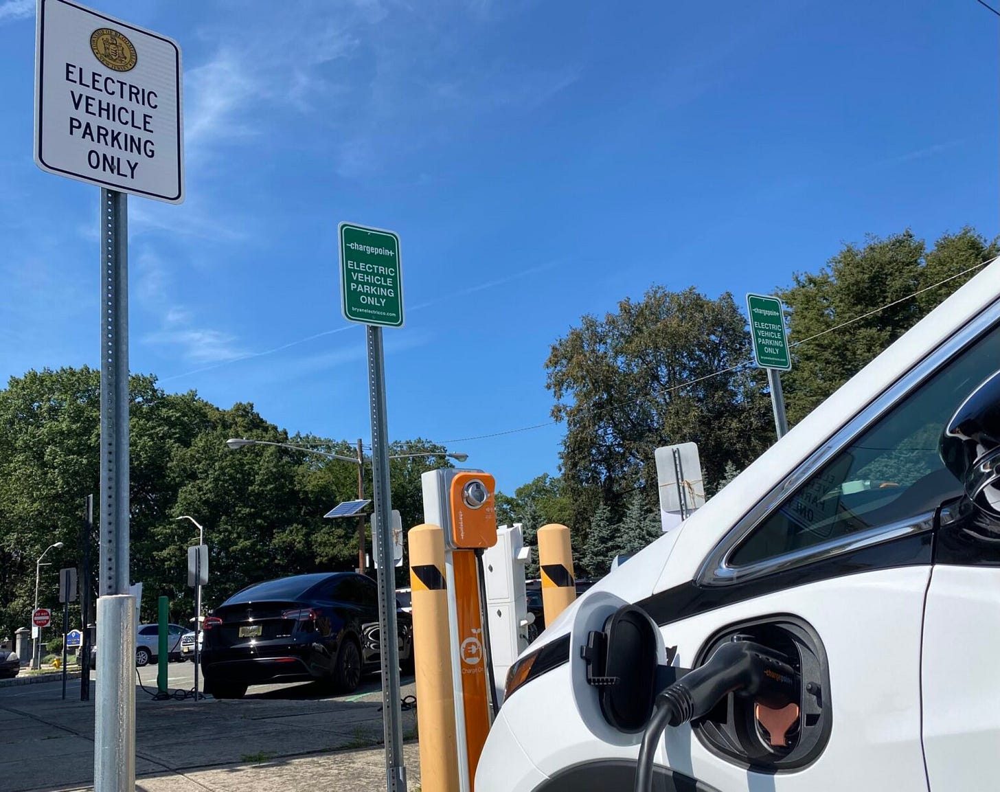 A white electric car is plugged into a charging station A white electric car is plugged into a charging station