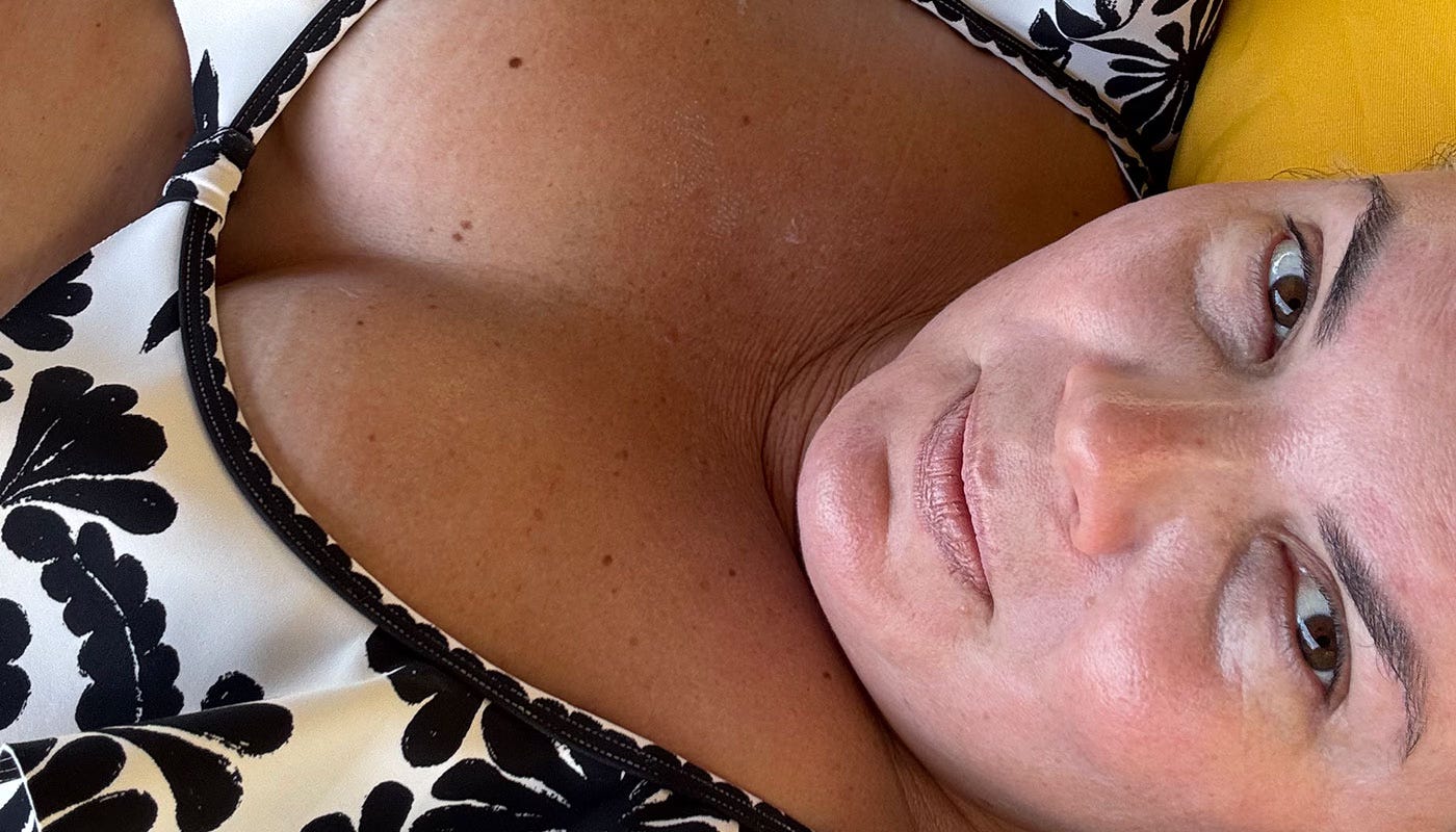 Close-up of a woman in a black and white patterned swimsuit reclining on a lounge chair