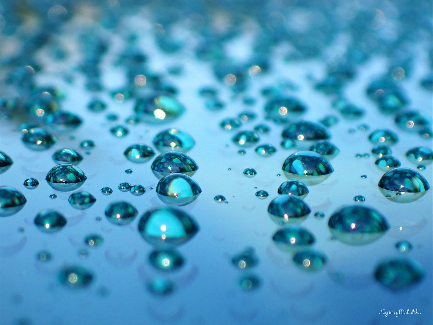Morning sun melts window frost, creating an ocean of turquoise droplets.