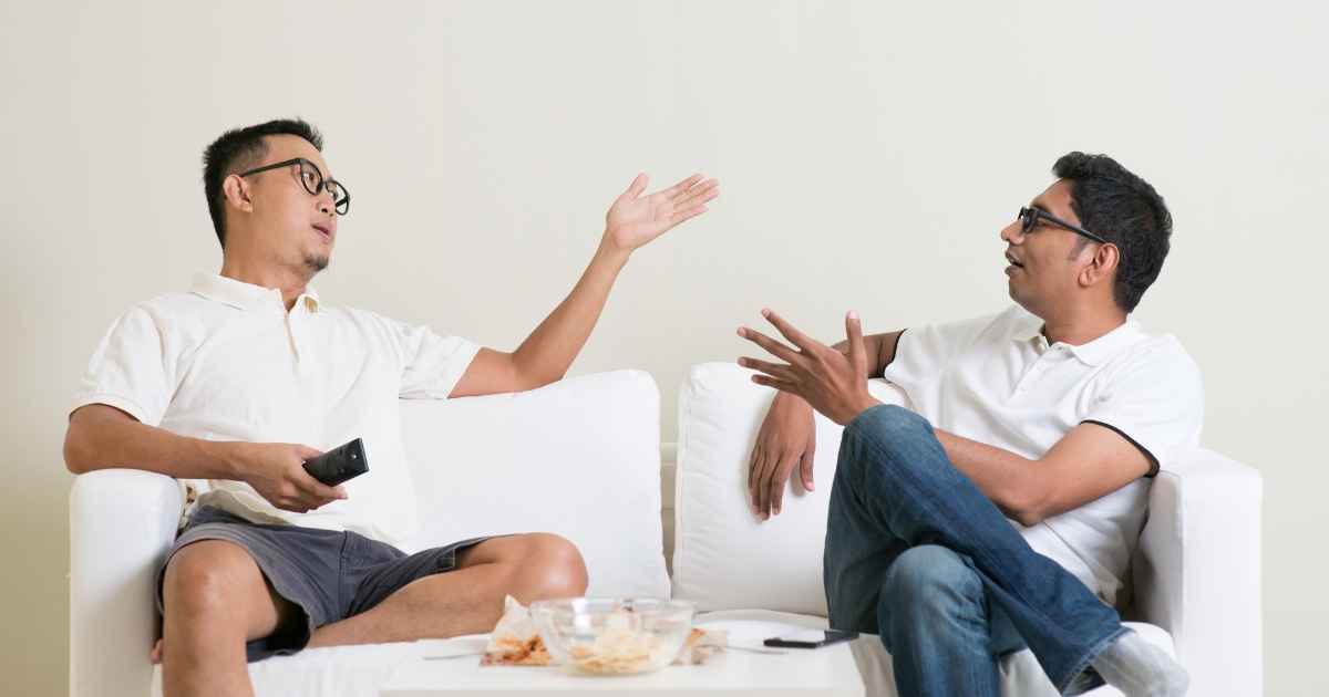 Two guys sat on the sofa having an argument