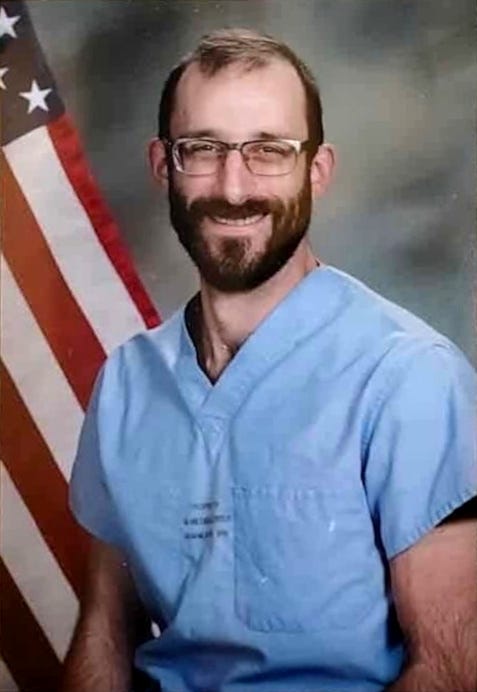 Headshot of a bearded Pretti wearing glasses and smiling against a white background