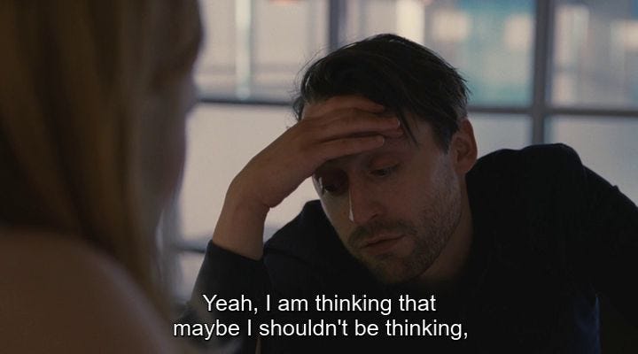 This may contain: a man sitting in front of a woman who is holding her head