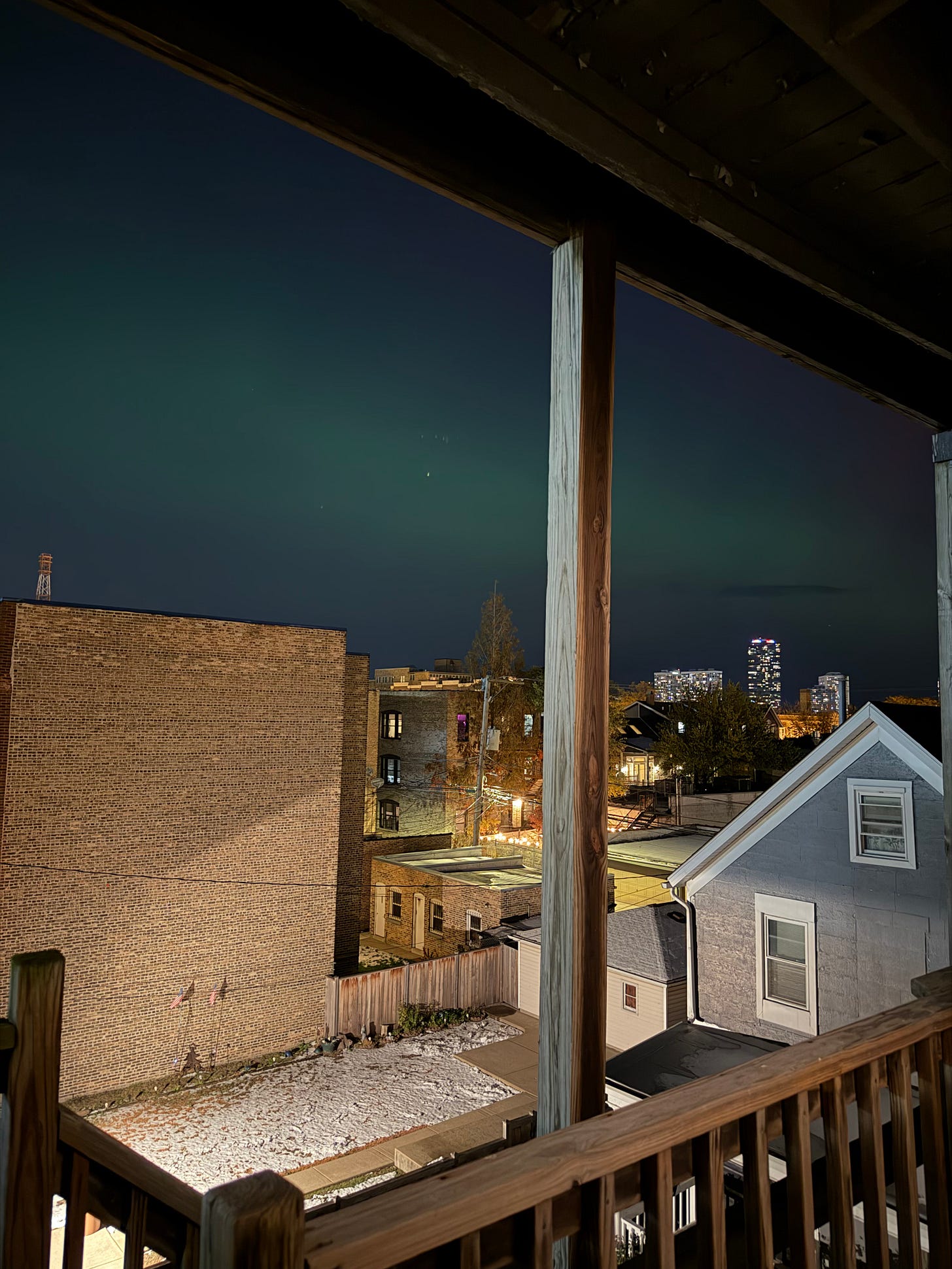 A few brick buildings and the night sky, which has a distinct teal streak through it