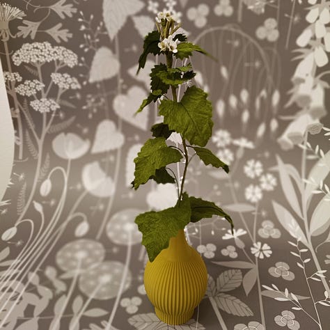 Brightly coloured paper flowers photographed against a backdrop of elegant, hedgerow inspired wallpapers.