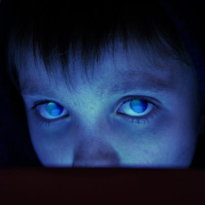 close up of young boy, blue light on the upper half of his face close up of young boy, blue light on the upper half of his face