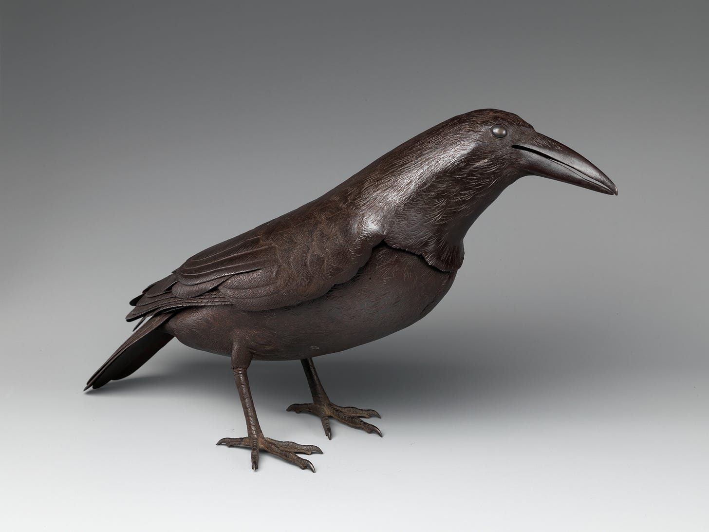 "This raven was fashioned by hammering and embossing steel––a most intractable medium––into a being of remarkable vitality. Though motionless, the bird is caught in a lifelike pose and full of expression. The conspicuously large size and shape of the beak distinguishes it from a crow. It was designed as an okimono, or ornament for display in the ceremonial alcove (tokonoma) of a Japanese reception room. Because of its large size and fine quality, we may imagine this work was commissioned for a wealthy daimyo patron."
