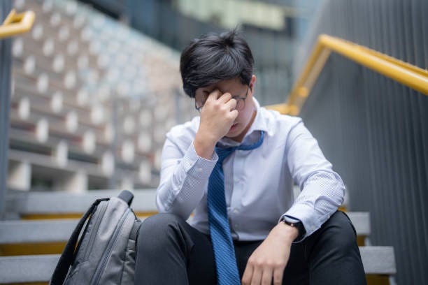 a young, anxious businessman with his head in his hands, sitting outside his building - job loss stock pictures, royalty-free photos & images
