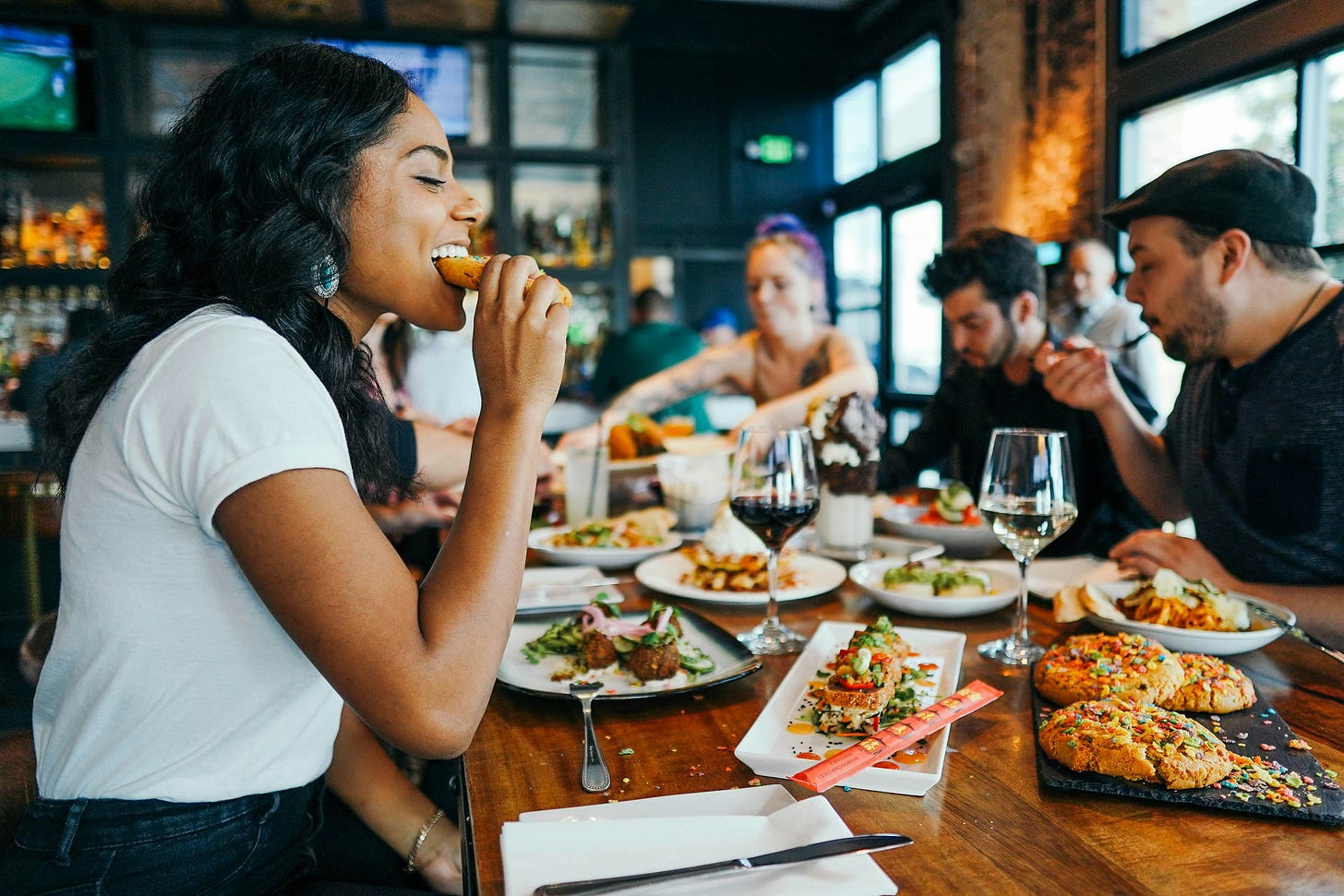 a pretty black woman eating at a table full of other people eating