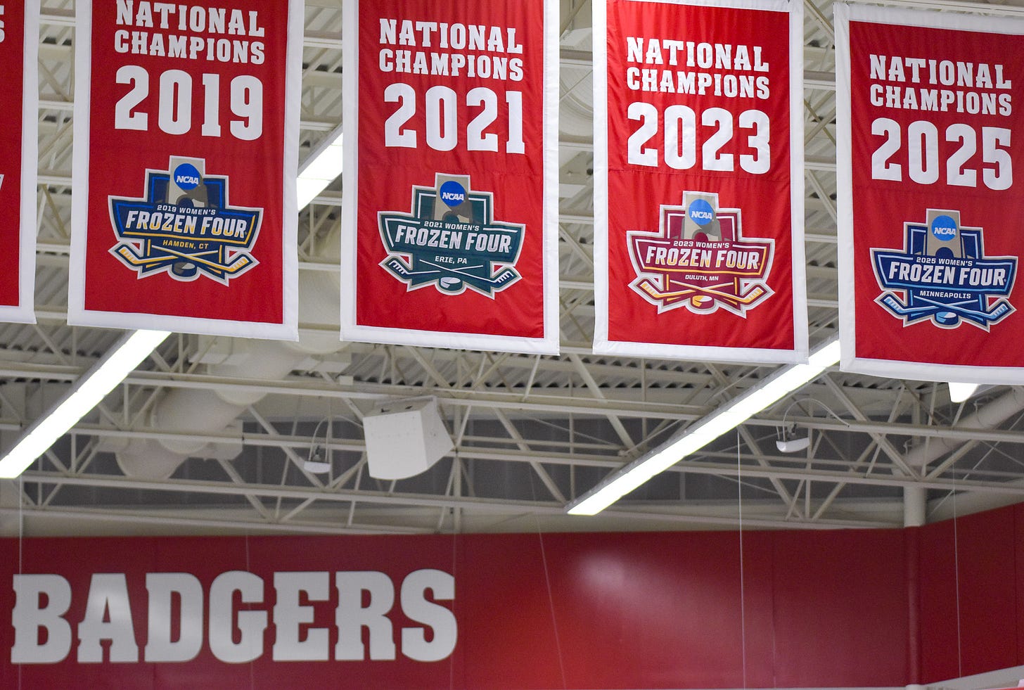 national championship banners hanging inside LaBahn Arena for the 2019, 2021, 2023, and 2025 seasons