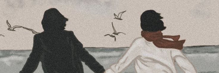 This may contain: two people are walking on the beach with birds flying above their heads and one is wearing a scarf This may contain: two people are walking on the beach with birds flying above their heads and one is wearing a scarf