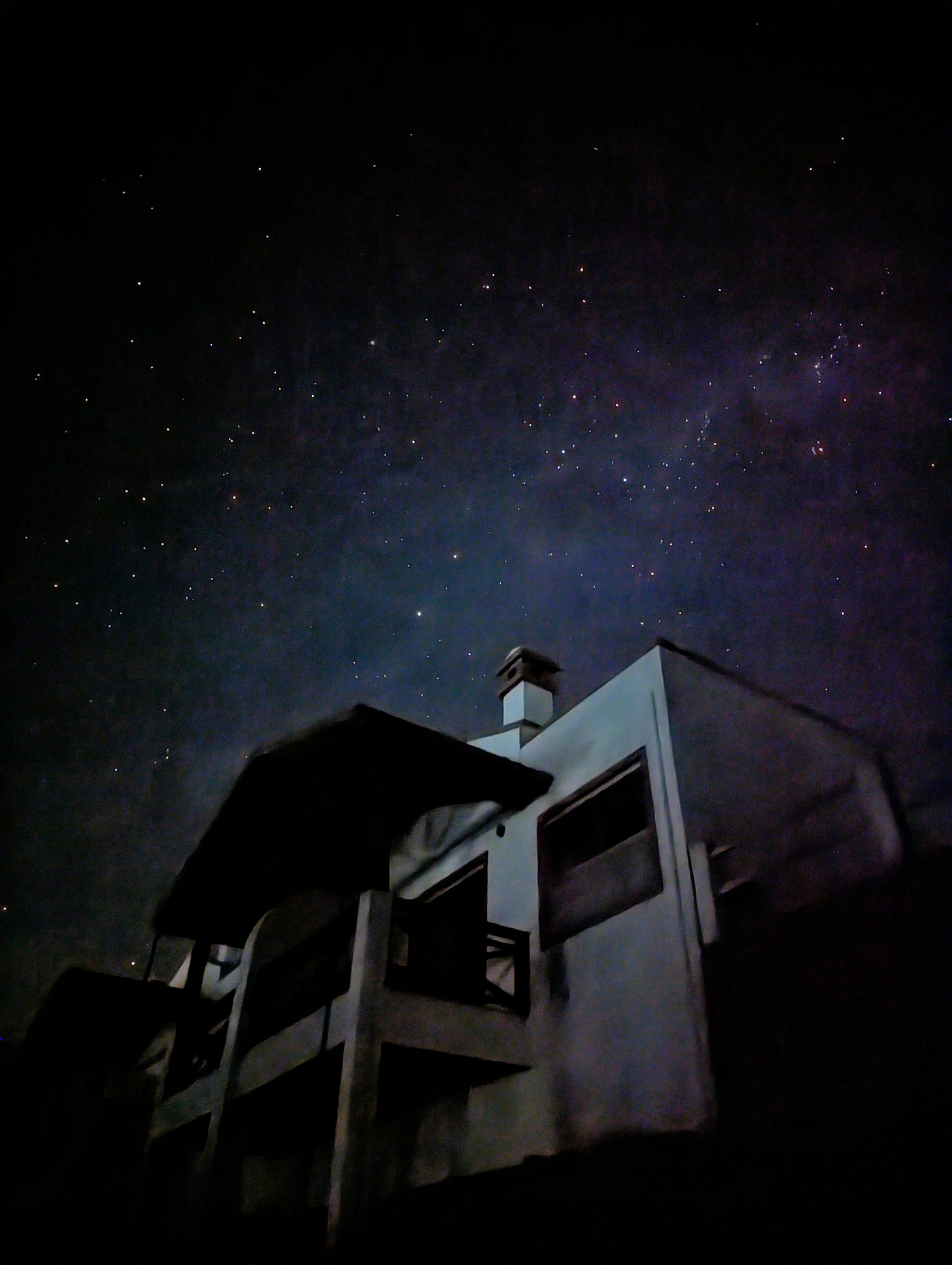 Darkened chalets at night, with a starry sky above them.