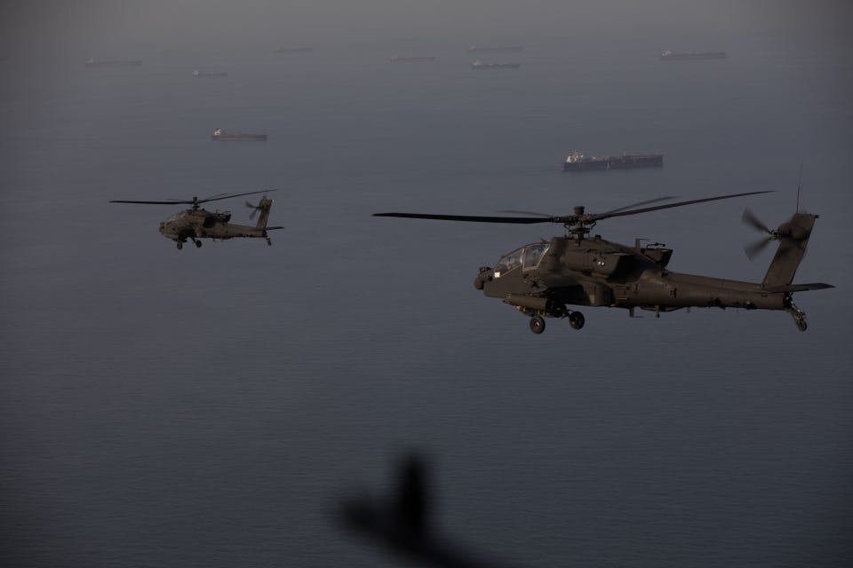 AH-64 Apache helicopters fly above the Strait of Hormuz during a patrol, April 17. Commercial ships are visible on the water below. AH-64 Apache helicopters fly above the Strait of Hormuz during a patrol, April 17. Commercial ships are visible on the water below.