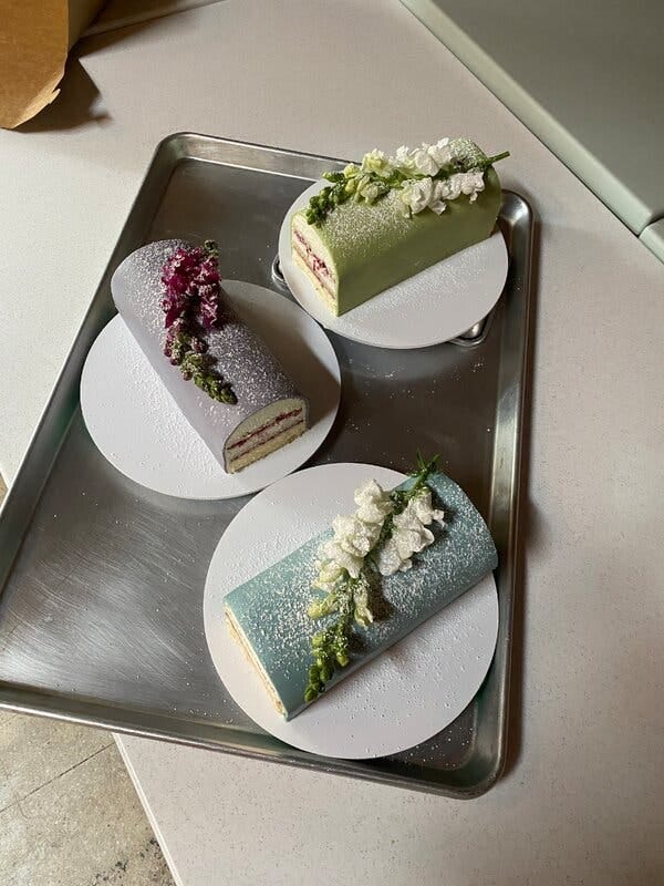 Three domed princess cakes on a metal tray each decorated with a branch of flowers.