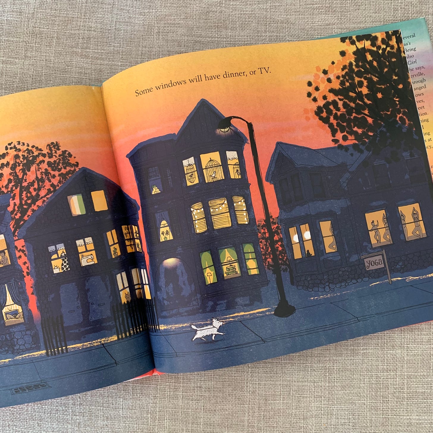 Colorful spread in a picture book of houses at dusk, windows lit. 