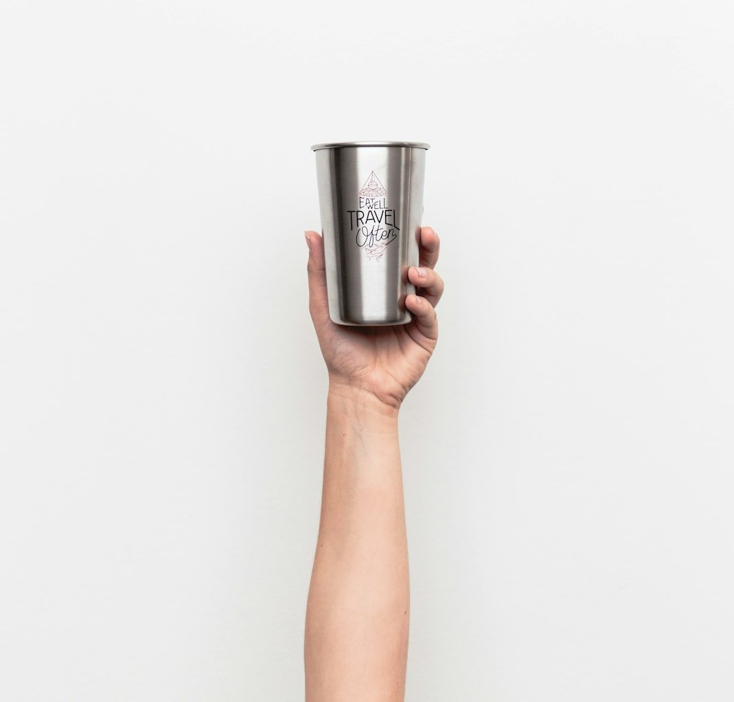 person holding gray stainless steel drinking cup