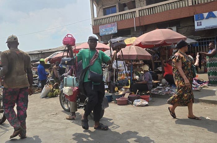 A man on the street, holding up many women’s purses for sale. A man on the street, holding up many women’s purses for sale.