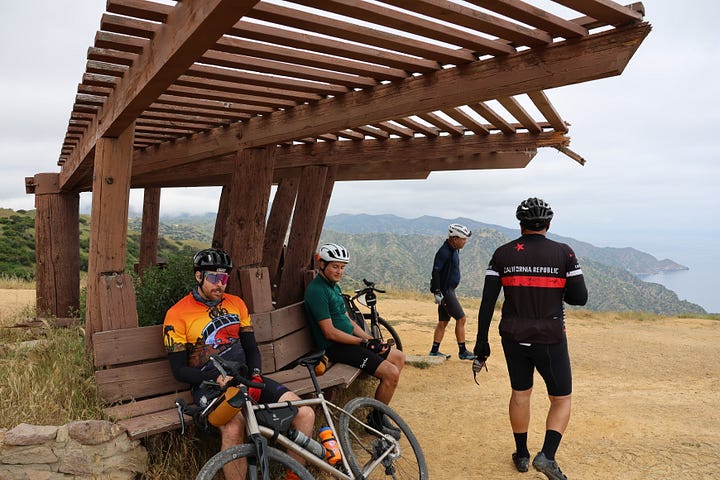 Cyclists climbing up a steep road and reaching a vista point at the top of the climb