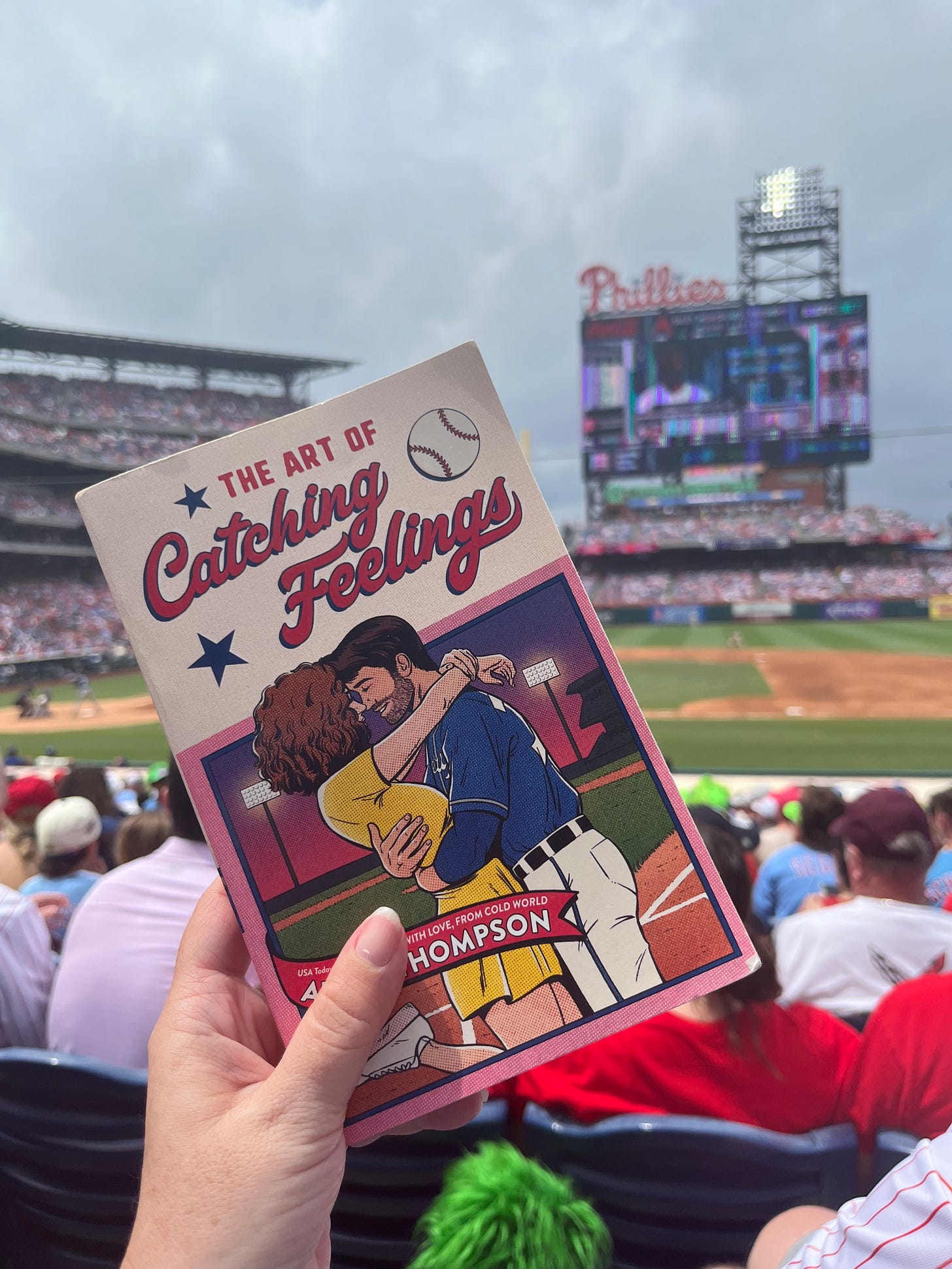 Picture of THE ART OF CATCHING FEELINGS held up in front of the field at Citizens Bank Park
