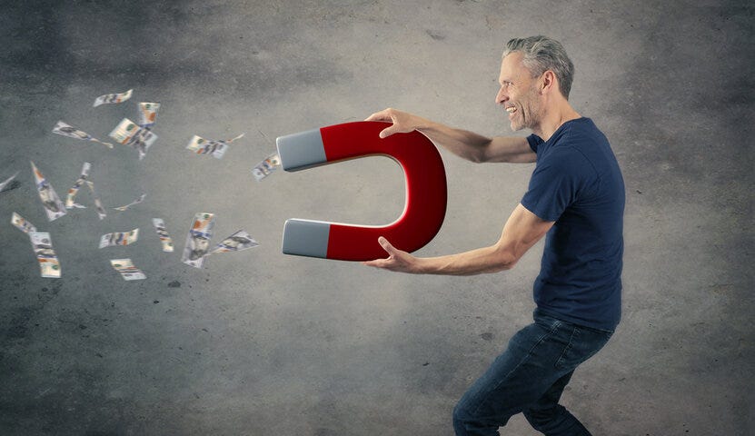 Happy man with a big magnet attracting money