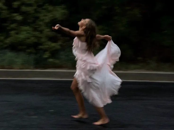 This may contain: a woman in a white dress is running down the street with her arms spread out