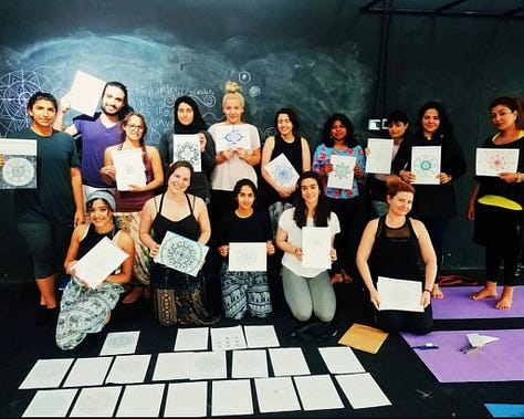Three side-by-side images of a woman leading movement and healing-centered workshops. Left: she smiles while standing next to a Puma x Rihanna event sign, indicating a yoga class collaboration. Center: she poses with a diverse group of students proudly holding up certificates and drawings from a workshop, surrounded by papers on the floor. Right: she kneels on a yoga mat, gently holding a student’s hands in a moment of somatic connection and support.