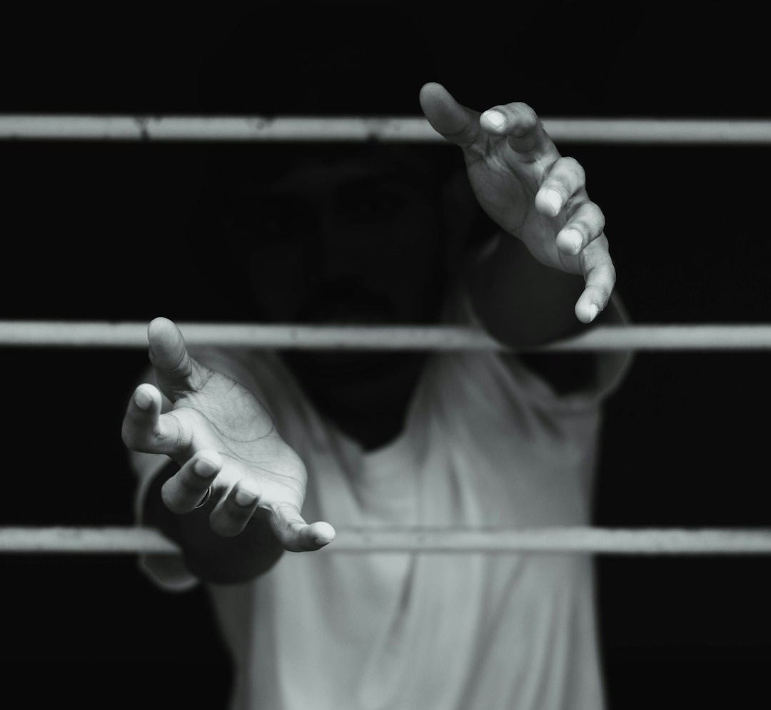grayscale photography of man in front of window