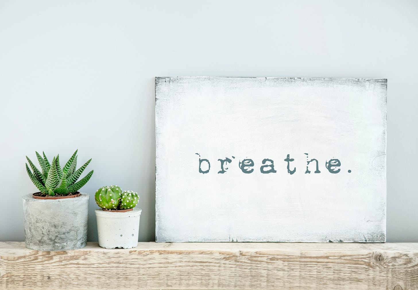 Sign saying breathe with plants next to it
