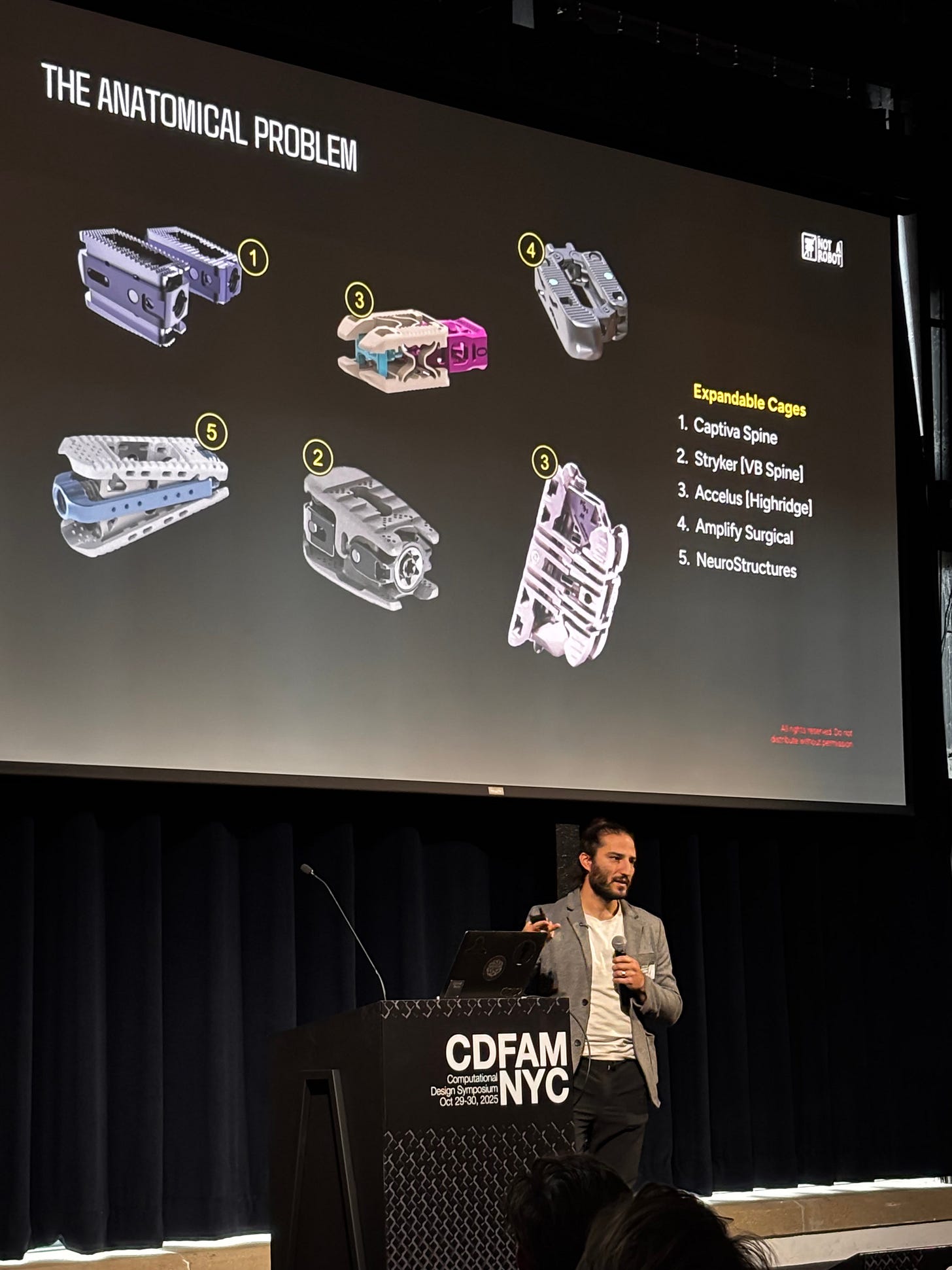 A presenter discusses the topic of expandable cages in a lecture at a design symposium. Illustrative images of various cage designs are displayed on a screen alongside corresponding labels numbered from 1 to 5.
