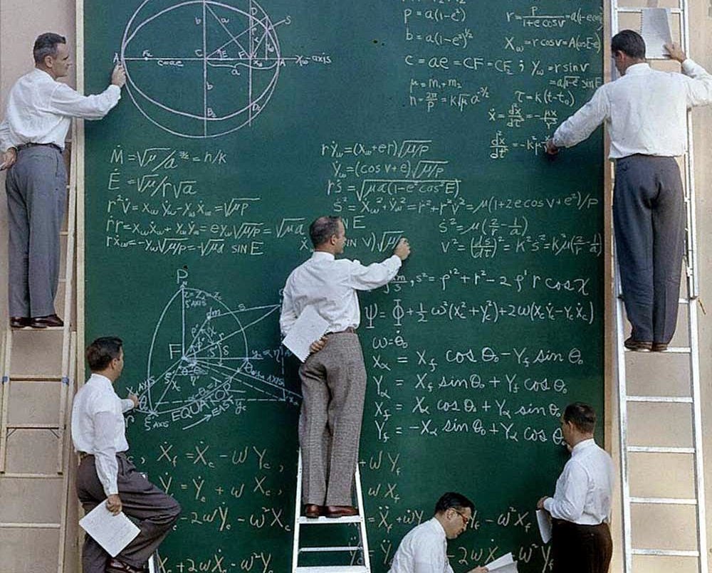 Six unidentified scientists uses a ladders and a large chalk board to work out equations for satellite orbits at Systems Labs, California, 1957.