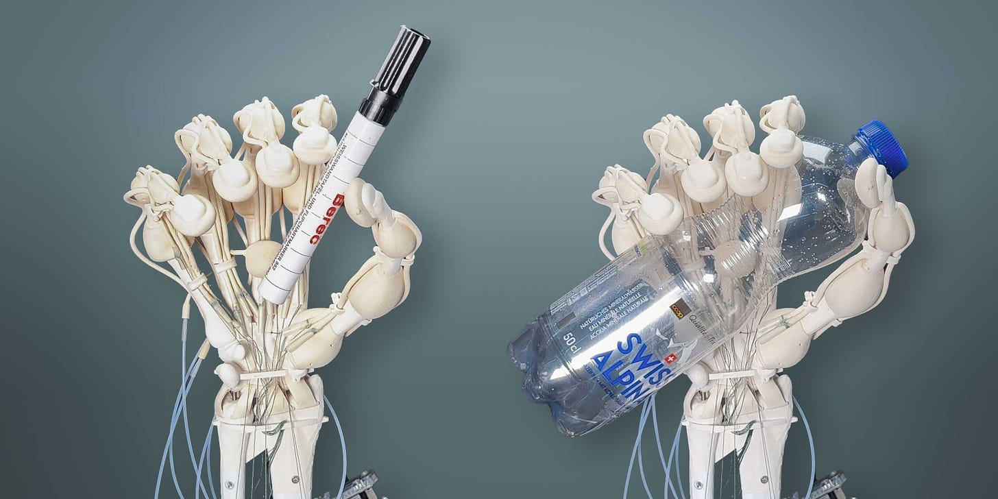 Two hands printed by a 3D-printer. The left one holds an Eding-Pen and the right one holds a bottle of water