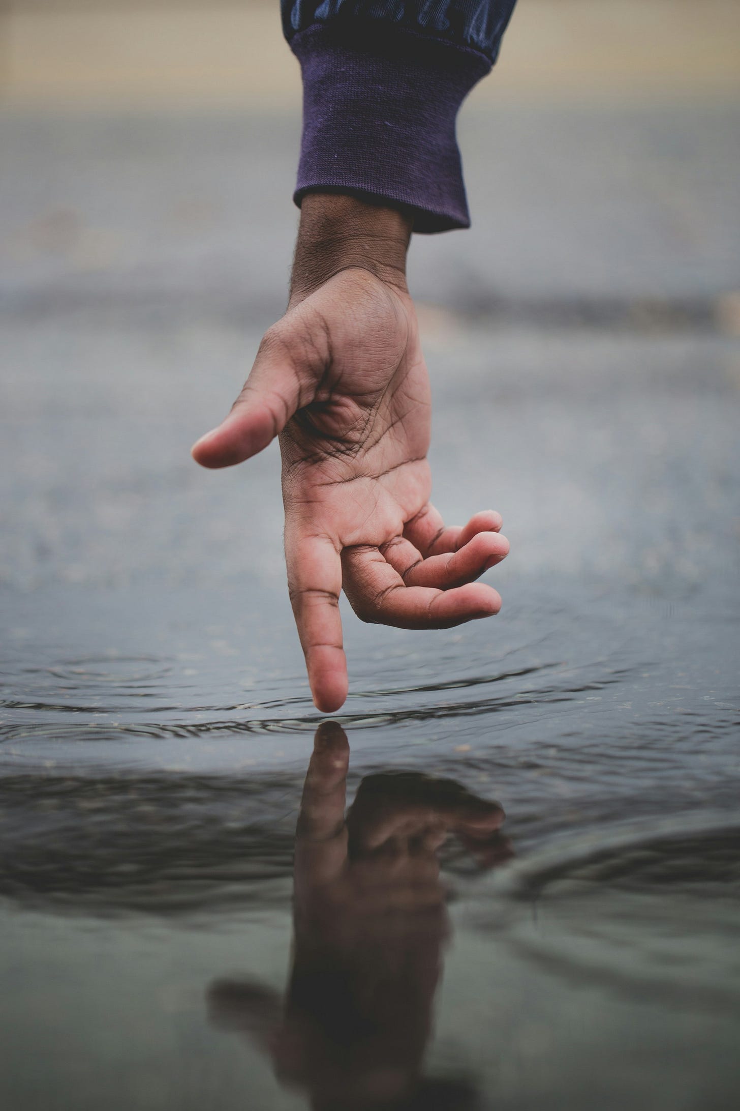 A hand touching its own reflection in the water. A hand touching its own reflection in the water.