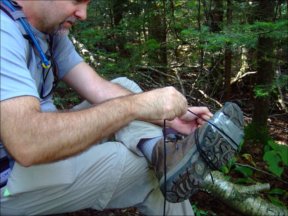 The author ties duct tape and rope around the sole of his hiking boot to keep it in place