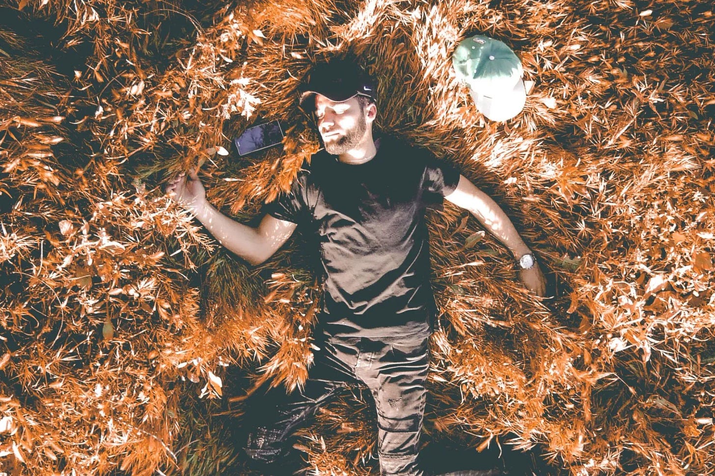 A young man lying in the grass feeling relaxed 