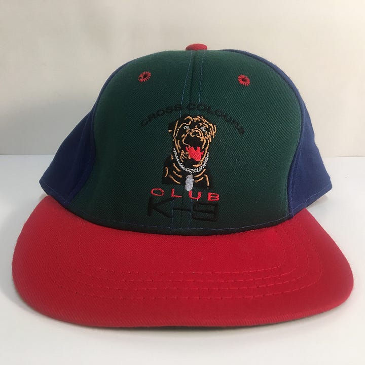 Images of brightly coloured shorts with graffiti, white t-shirt with the words Speak Yo Mind, multicolored cap with the words Cross Colours K-9 Club and image of a dog, and yellow, red, green, and blue patterned kente cloth shirt. 