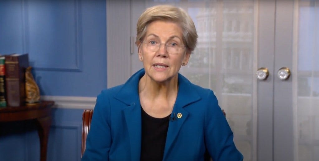 Senator Elizabeth Warren speaking at the Native CDFI 3rd Annual Policy Summit, wearing a blue jacket