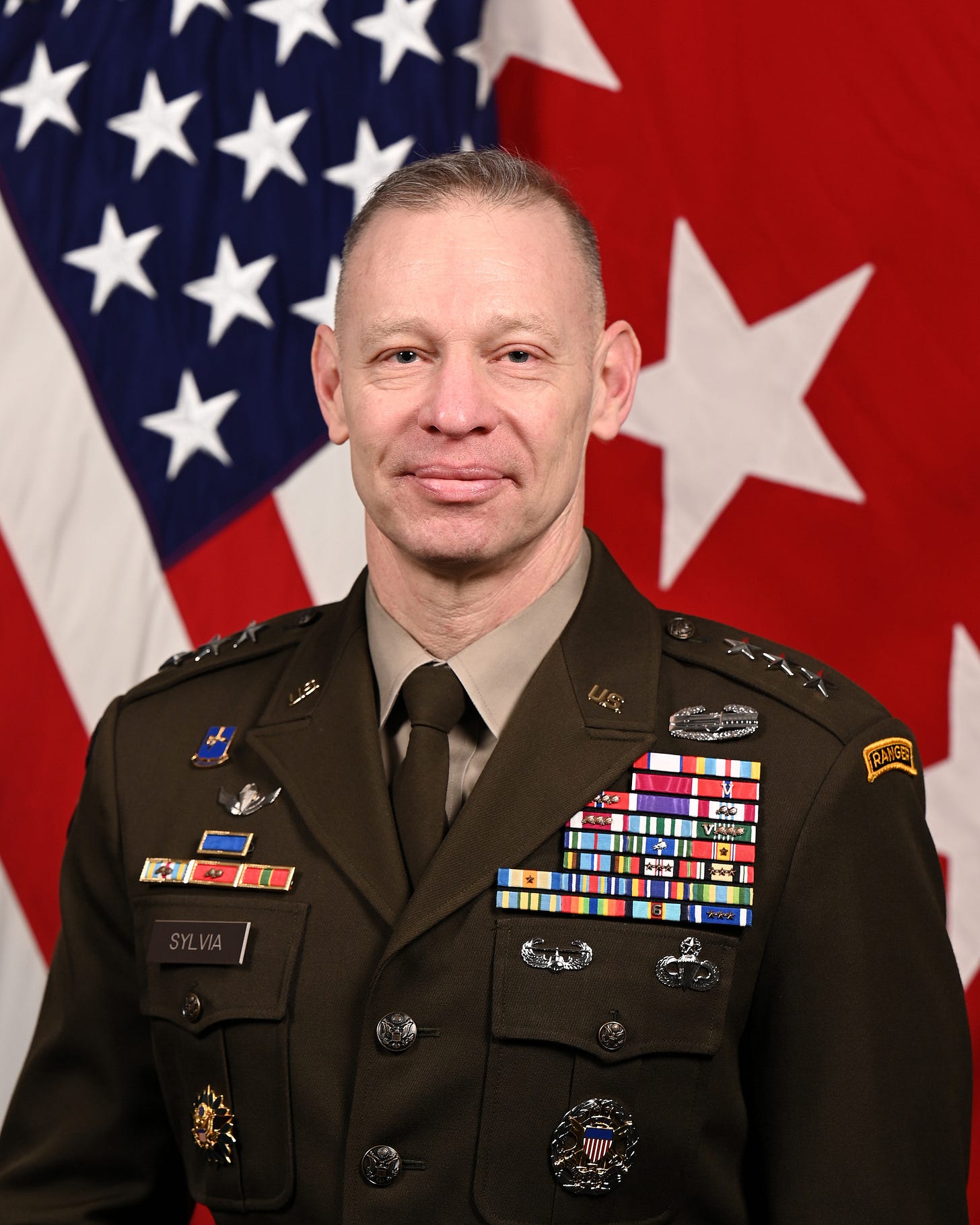 Official U.S. Army portrait of Lt. Gen. Brett G. Sylvia in uniform, in front of the U.S. flag and a lieutenant general's flag. Official U.S. Army portrait of Lt. Gen. Brett G. Sylvia in uniform, in front of the U.S. flag and a lieutenant general's flag.
